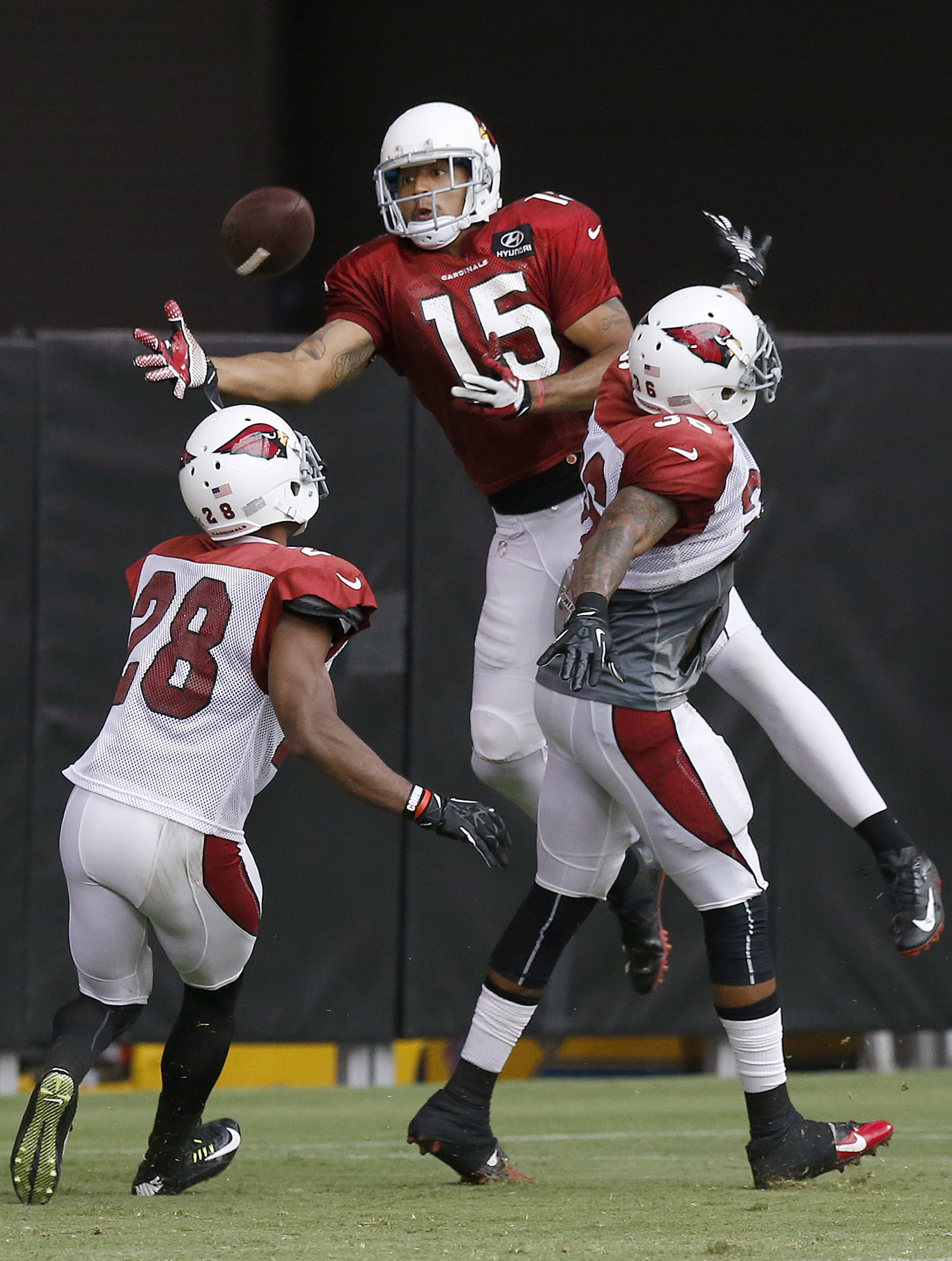 Arizona Cardinals' Justin Bethel (28) and Deone Buccanon (36) break up a pass intended for Michael Floyd (15) during NFL football training camp practice on Wednesday, July 30, 2014, in Glendale, Ariz. (AP Photo/Ross D. Franklin)